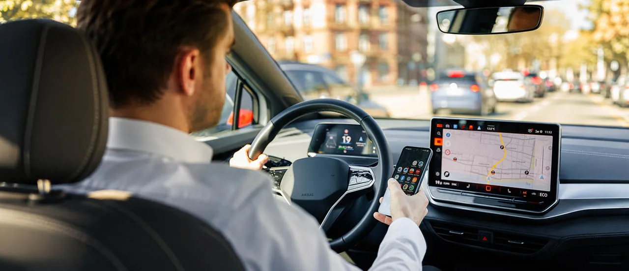 Mann mit Handy am Steuer