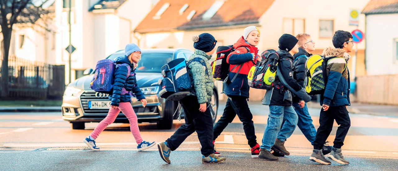 Schulkinder überqueren eine Straße